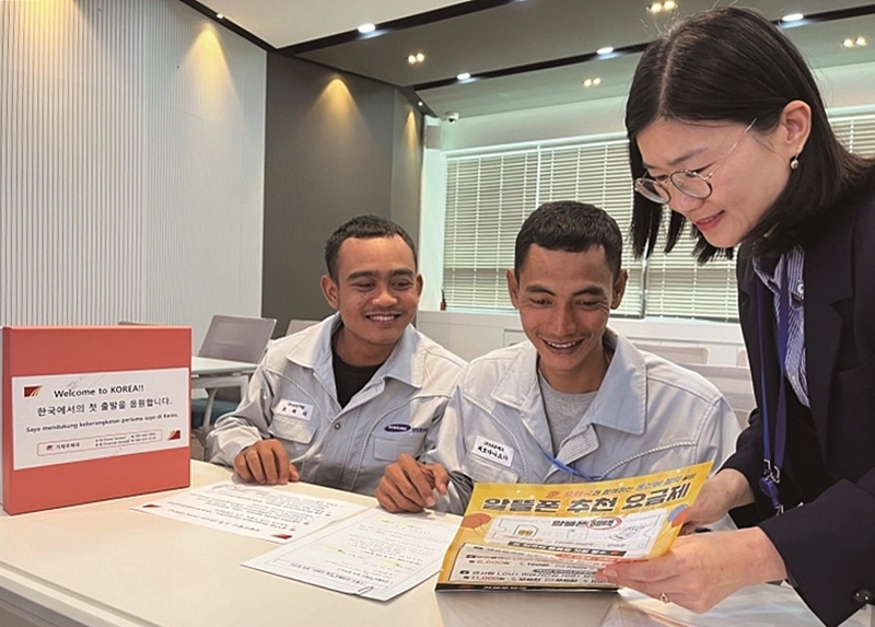 Foreign students, trainees and job seekers in Busan from Feb. 18 can receive up to 13% off international Express Mail Service. Shown are two foreign nationals learning about mail packaging and financial services at a post office. (Korea Post)  